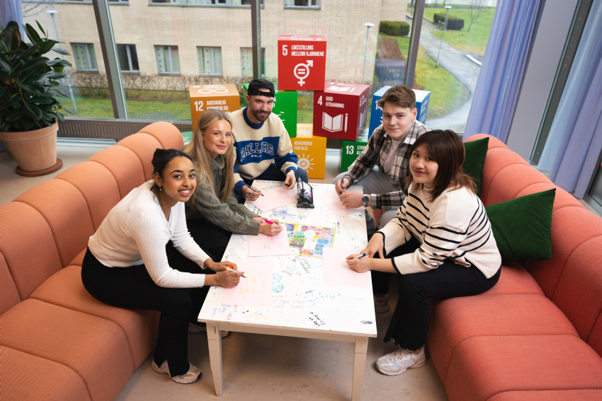 5 studenter, sitter i sofa og jobber rundt bord, på campus i Ålesund.
